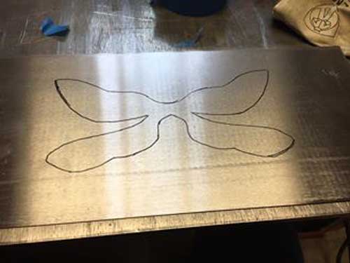 outline of dragonfly on metal, preparing to plasma cut